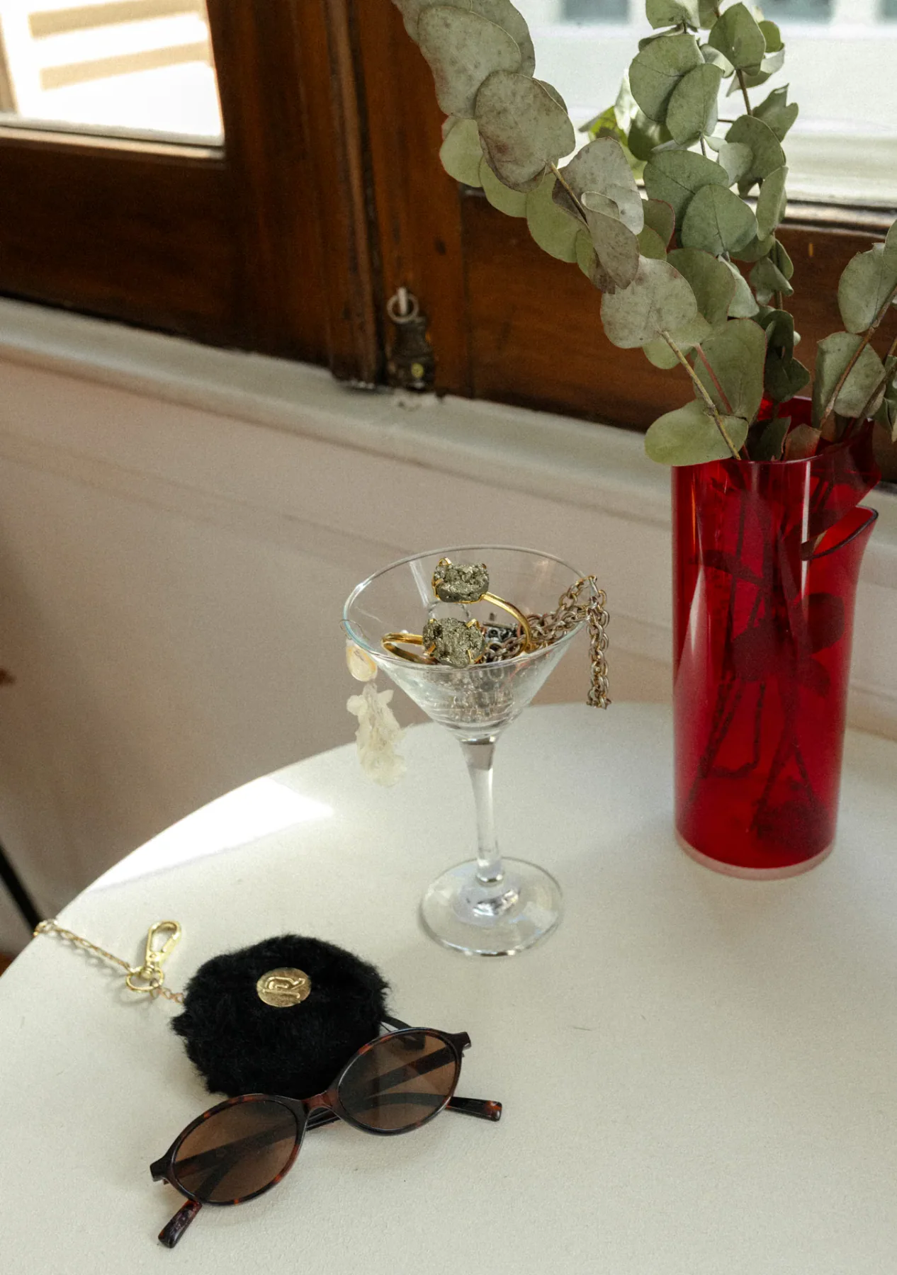 Copa reutilizada para guardar accesorios, junto a un florero y anteojos.