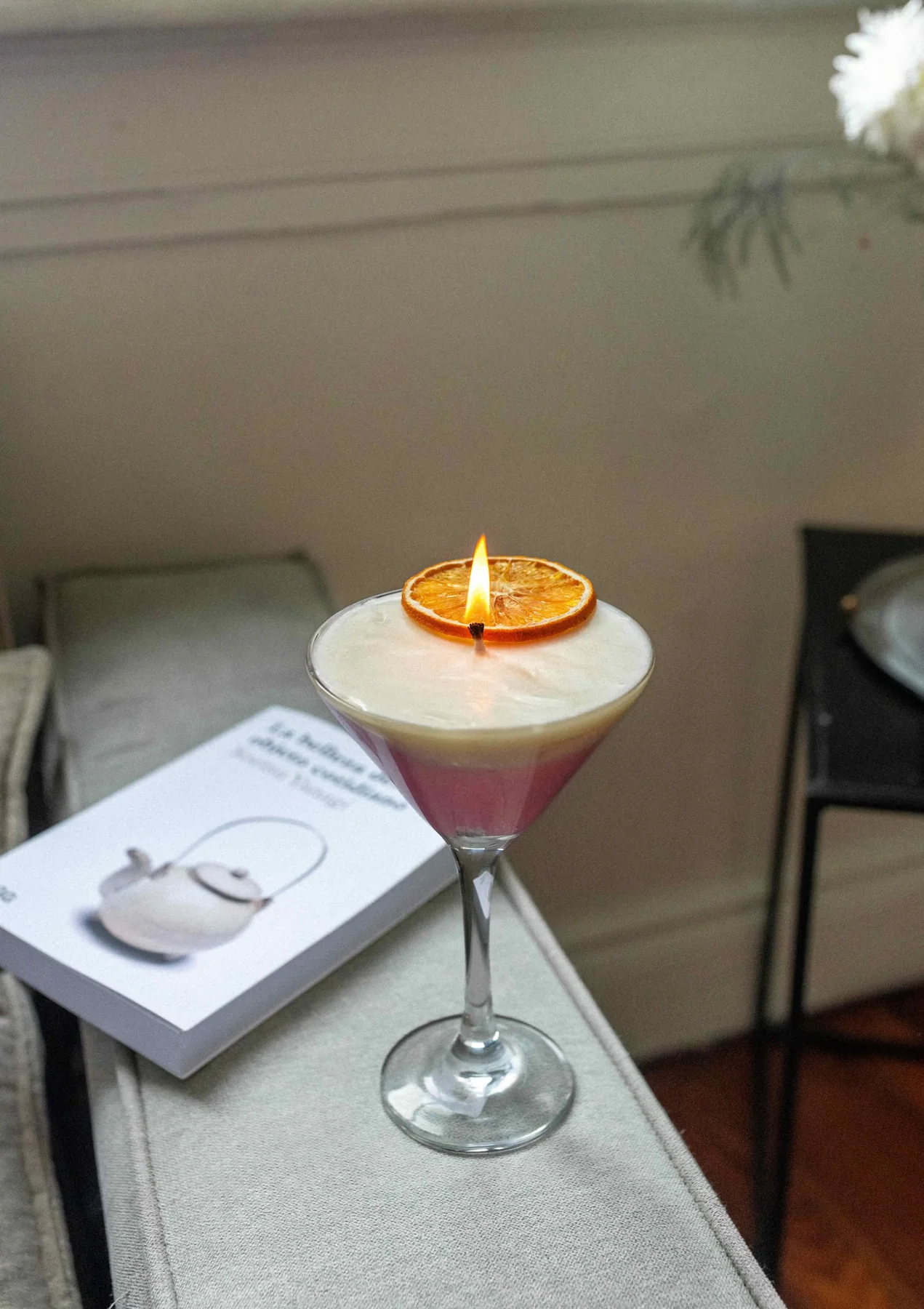 Vela en copa encendida junto a un libro.