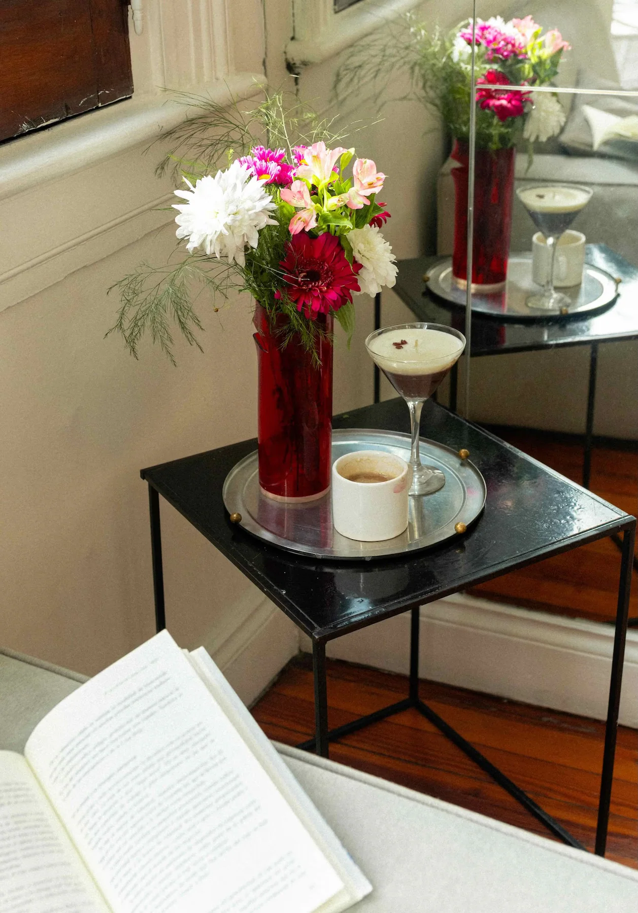Vela en copa con cerezas decorativas sobre una mesa con tela celeste y flores.