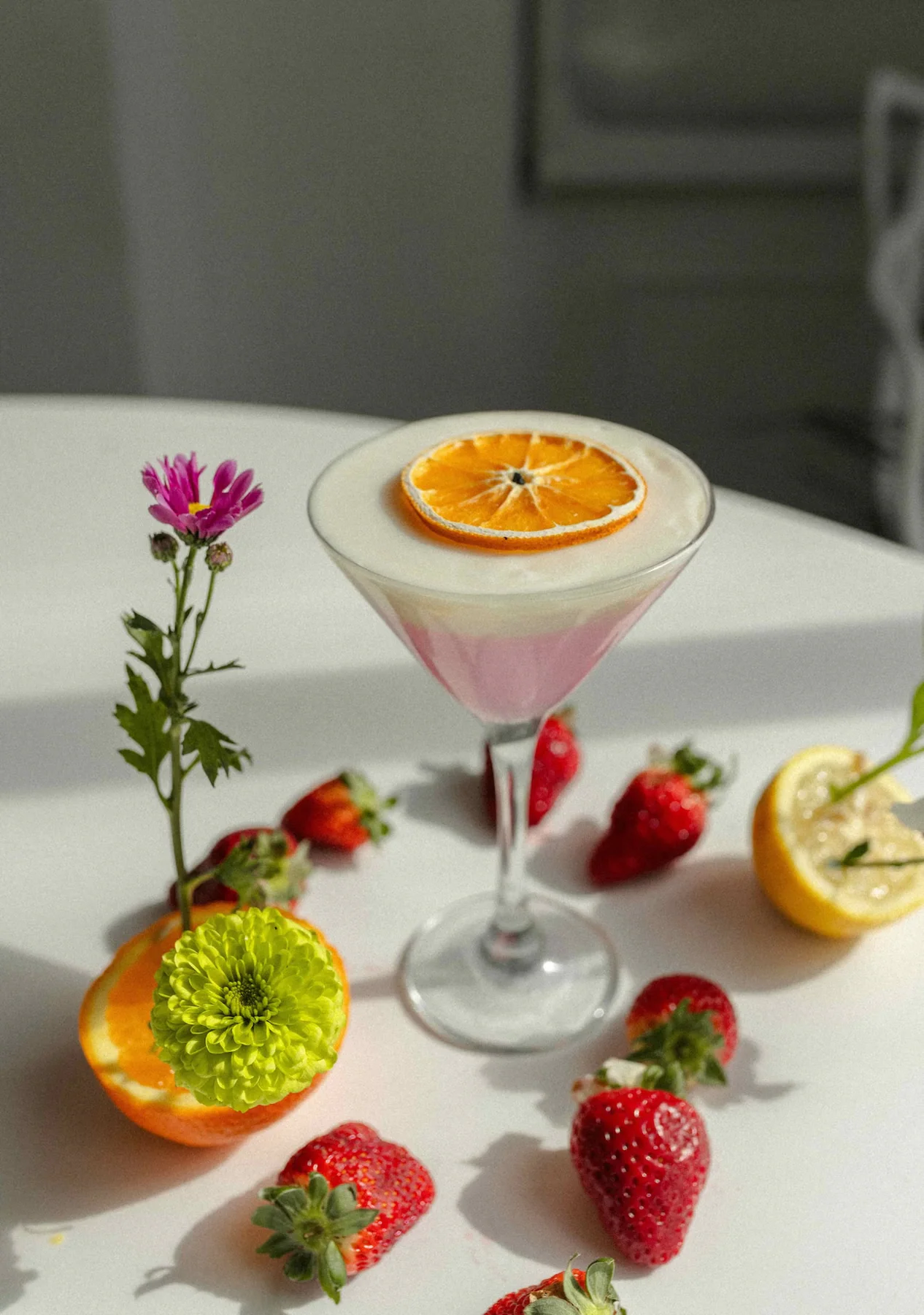 Vela en copa con rodaja de cítrico junto a frutillas, cítricos y flores.