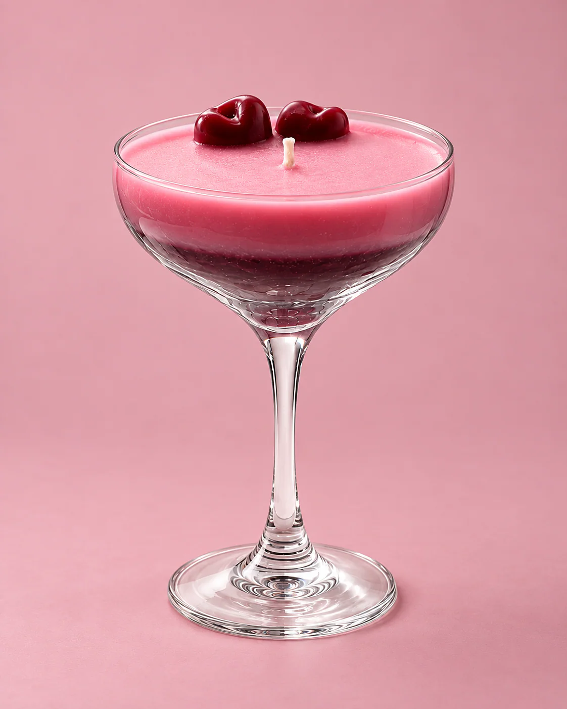 Vela Daikiri con cerezas decorativas en una copa, sobre fondo rosa.