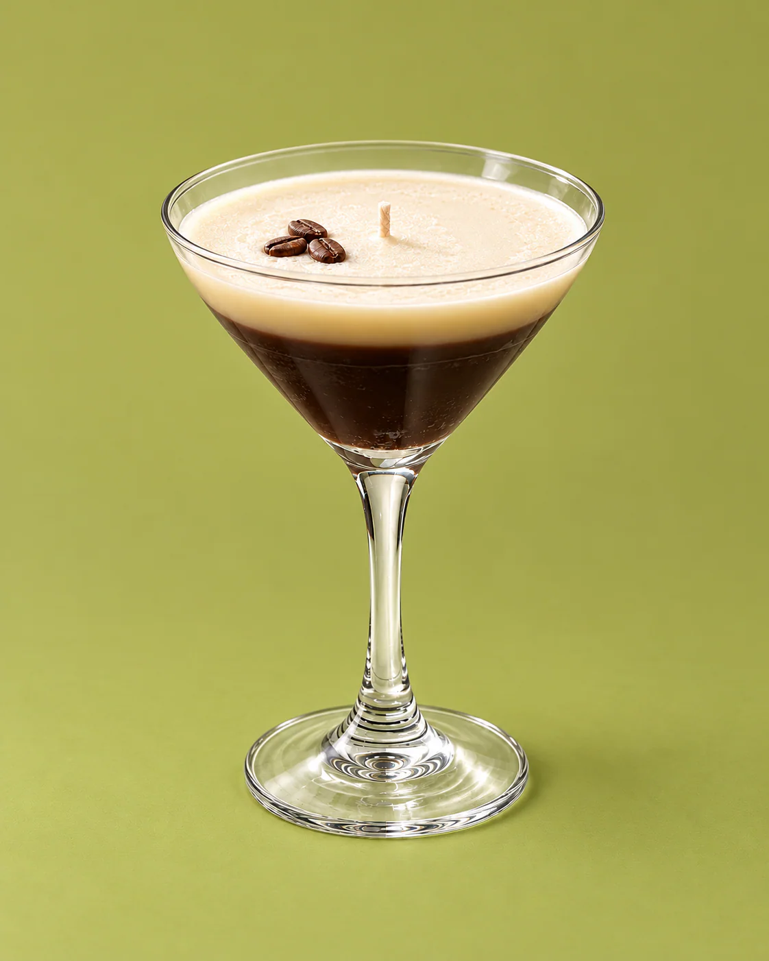Vela Espresso Martini en copa con granos de café, sobre fondo verde.