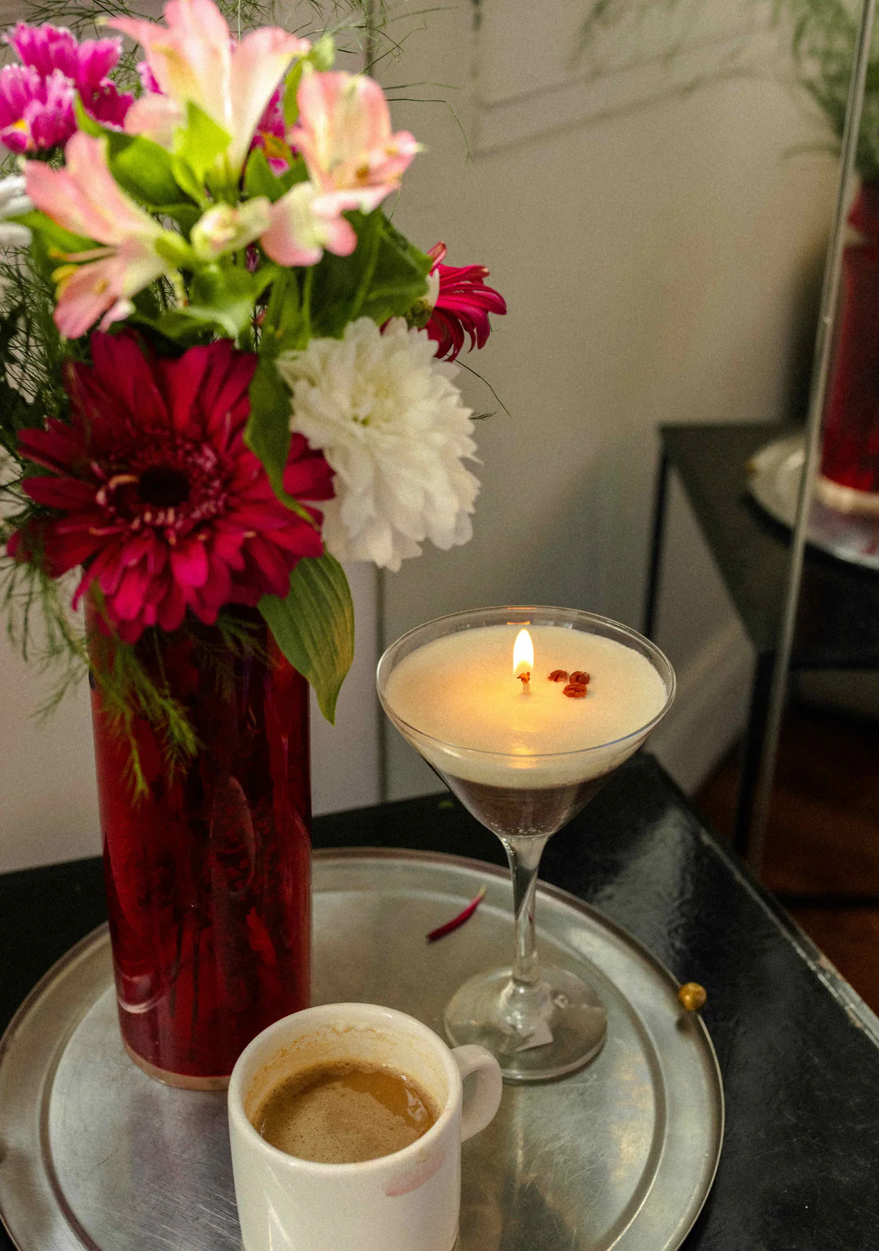 Vela Espresso Martini sobre una mesa junto a un café y un ramo de flores.